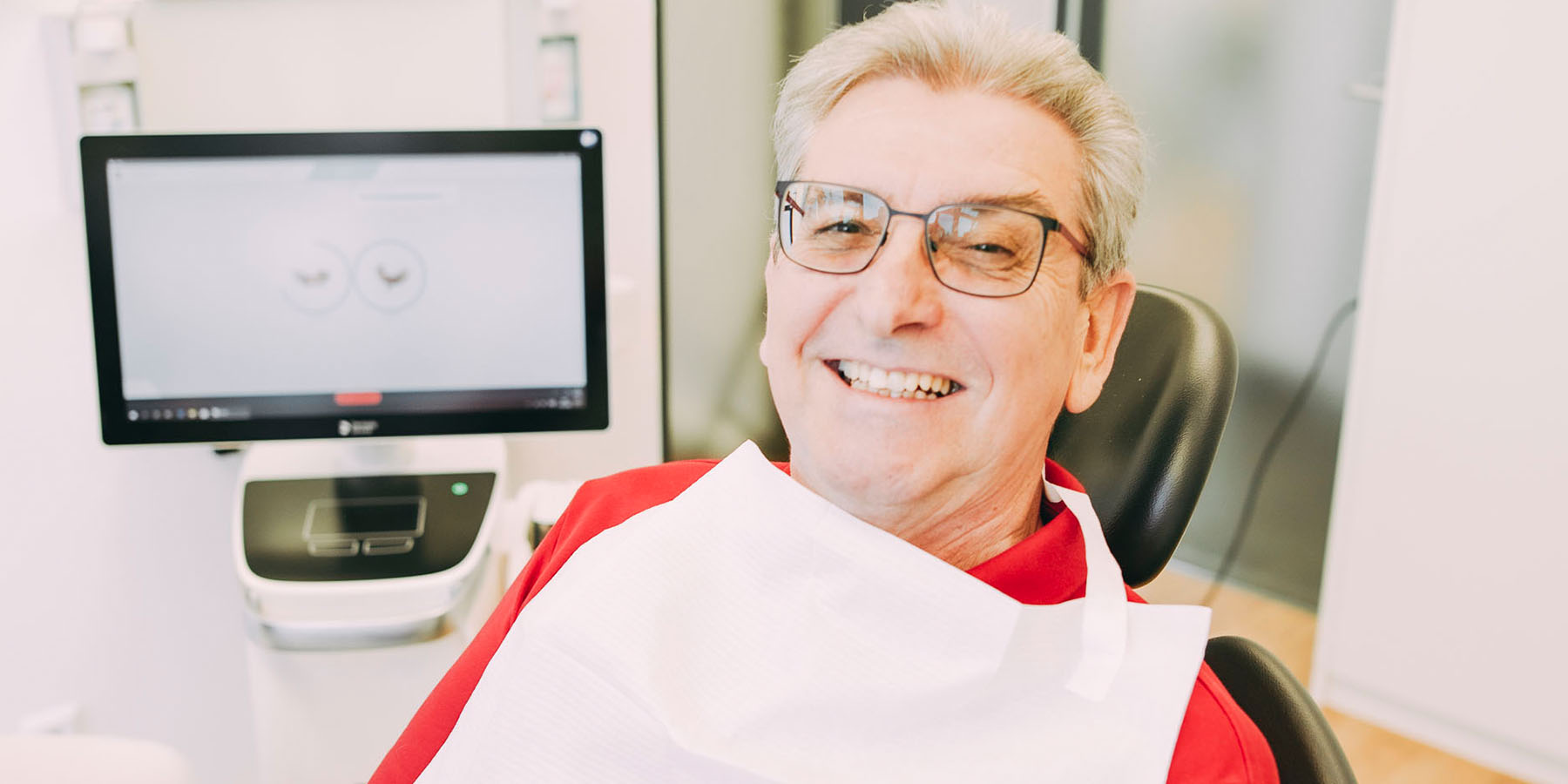 Ein älterer Patient lacht in die Kamera kurz vor der Anästhesie in der Zahnarztpraxis Matthias Theel in Hilpoltstein