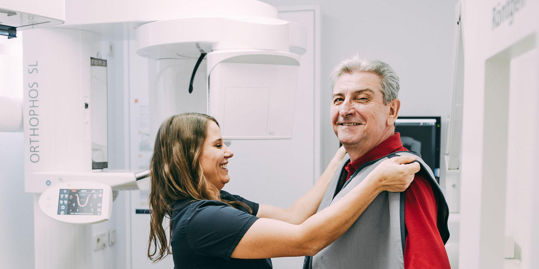 Eine Assistentin legt einem Patienten den Röntgenschutz an in der Zahnarztpraxis Matthias Theel in Hilpoltstein