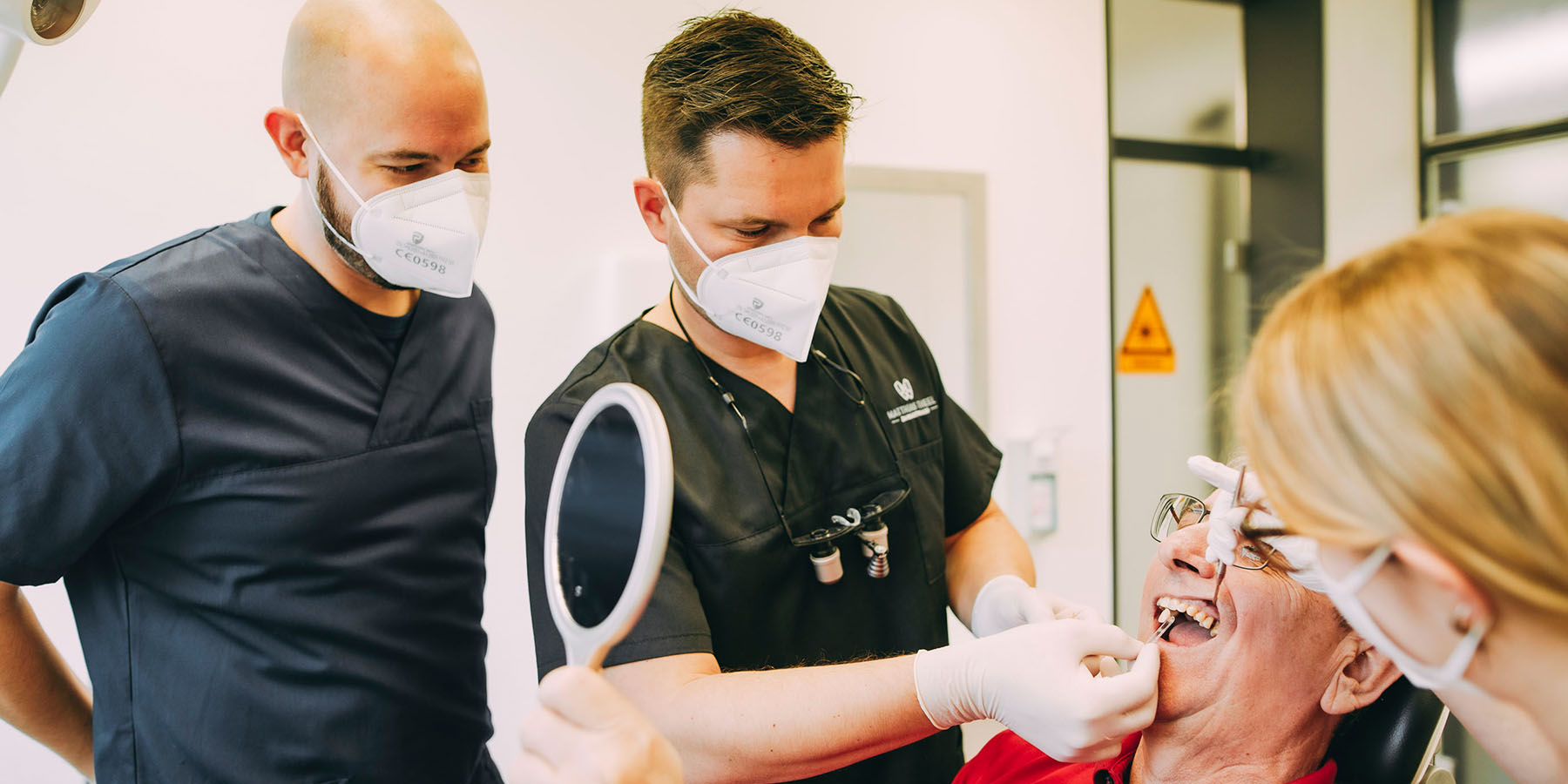 Dr. Matthias Theel mit einem Assistenten und einer Patienten mit Inlays und Onlays in der Zahnarztpraxis Matthias Theel in Hilpoltstein
