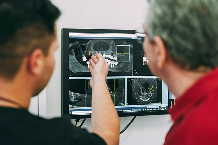 Dr. Matthias Theel zeigt einem Patienten seine Röntgenbilder in der Zahnarztpraxis Matthias Theel in Hilpoltstein