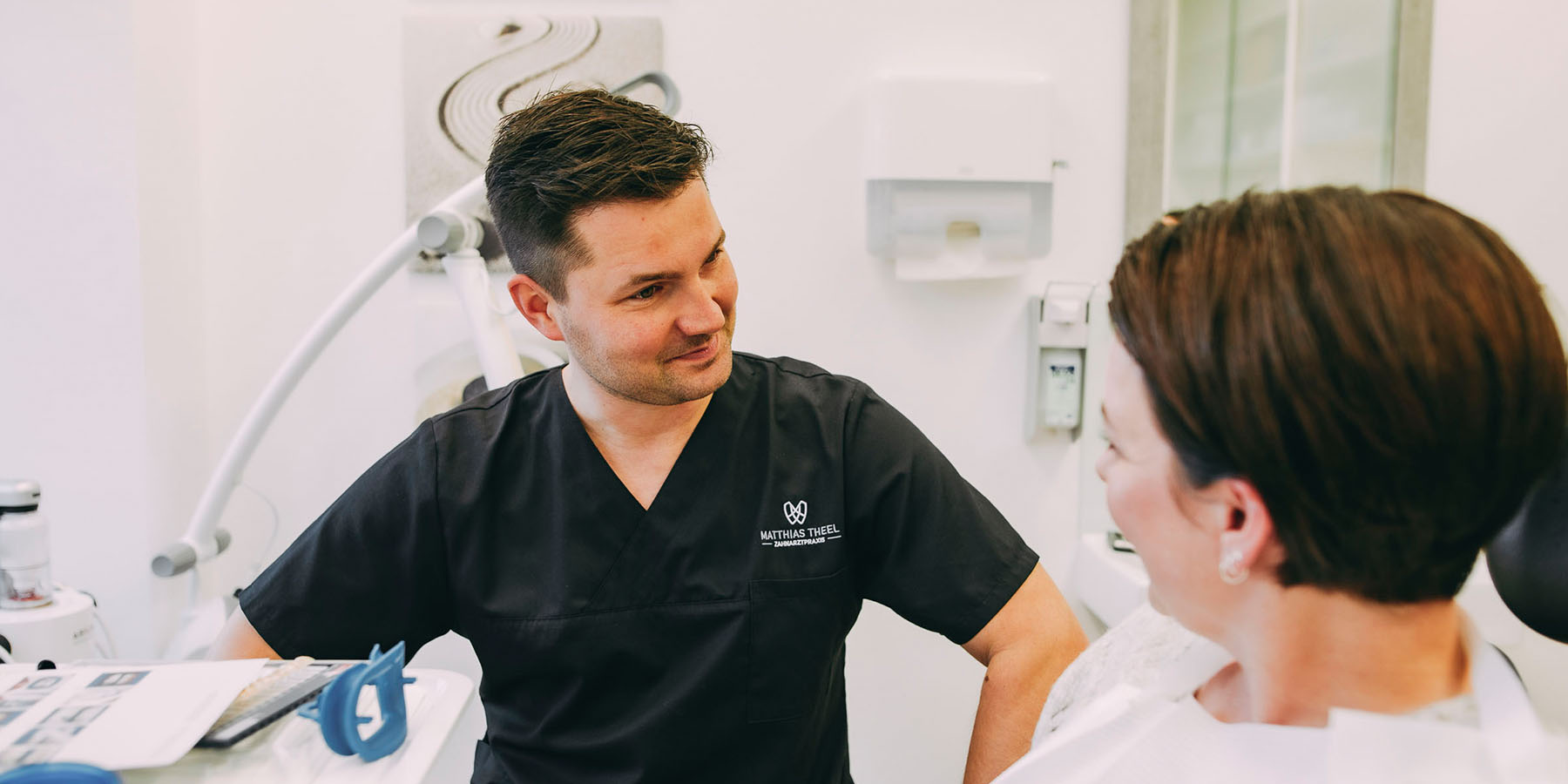 Dr. Matthias Theel in einem Gespräch mit einer Patientin während einer Paro-Behandlung in der Zahnarztpraxis Matthias Theel in Hilpoltstein