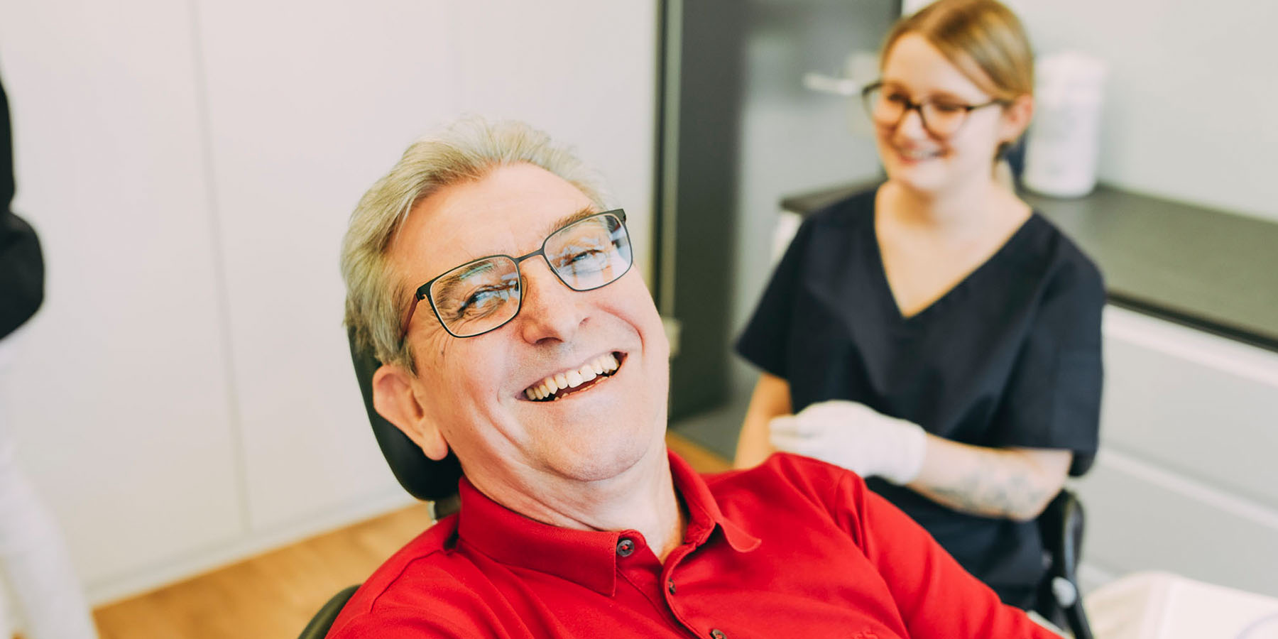 Ein älterer Patient lacht in die Kamera mit seinen Zahnimplantatenin der Zahnarztpraxis Matthias Theel in Hilpoltstein